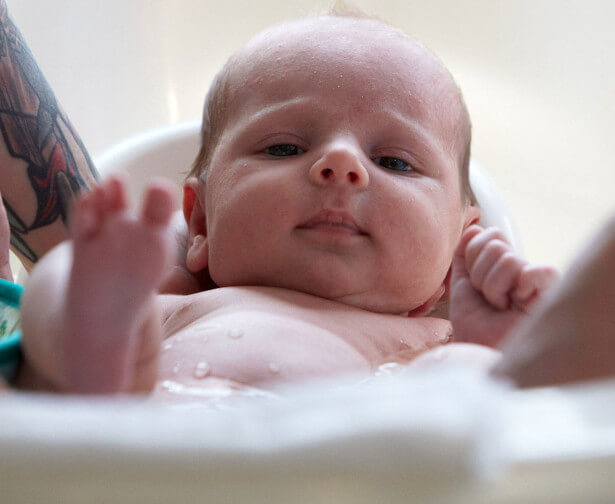 washing newborn in baby bath tub with Johnson's® CottonTouch™ newborn product